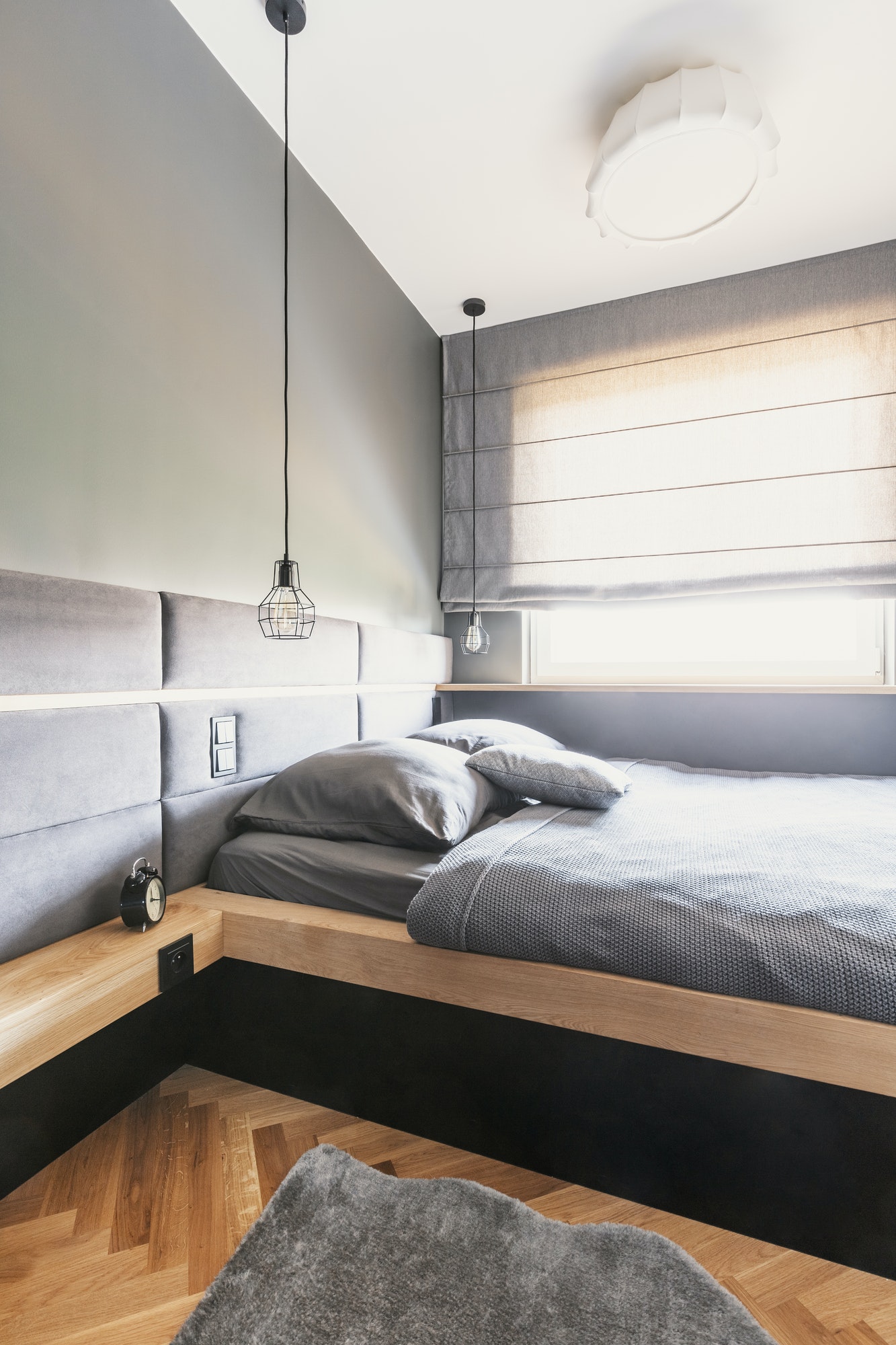 Grey sheets and cushions on wooden bed in minimal bedroom interi Grey sheets and cushions on wooden bed in minimal bedroom interi